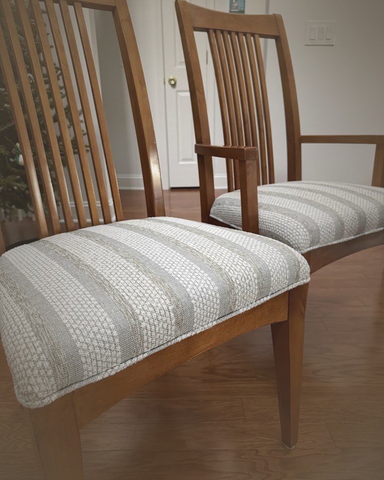 A pair of wood-frame dining chairs reupholstered in woven striped seats